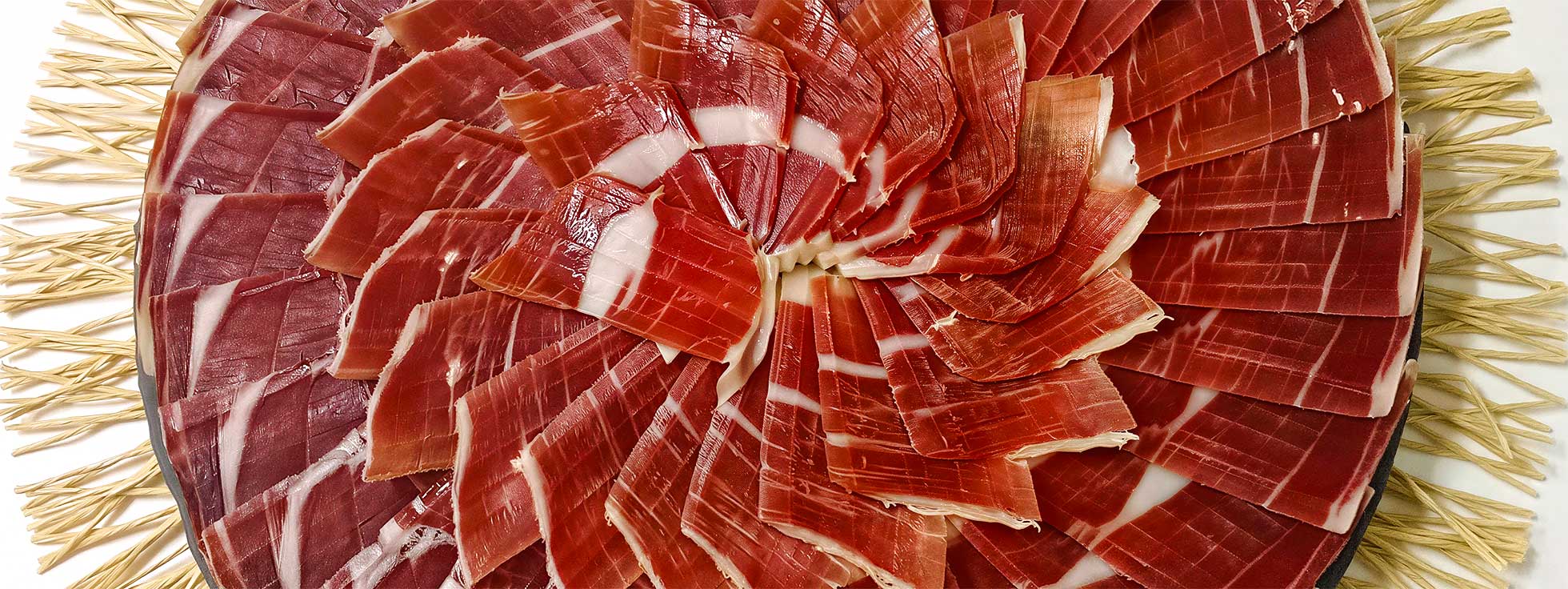 Primer plano de un plato de jamón cortado por un profesional.