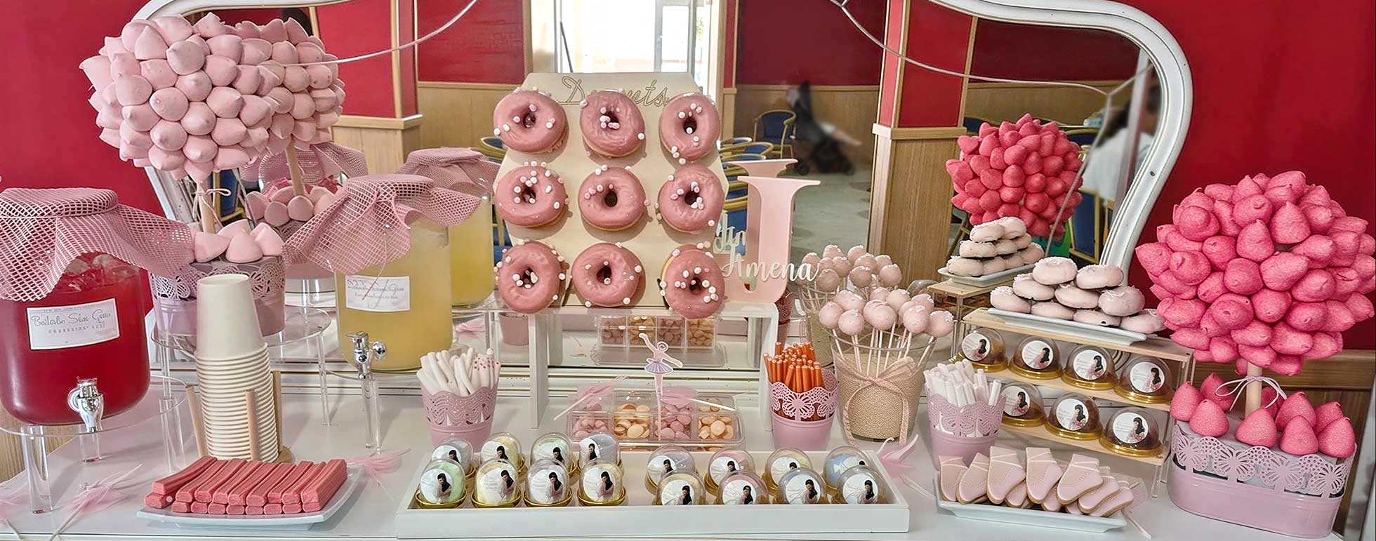 Mesa de dulces decorada en color rosa con donuts y nubes de azúcar.